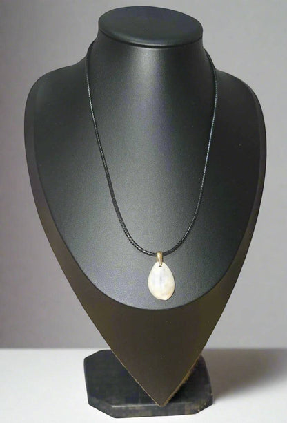 KRE PRIME handcrafted teardrop shell pendant necklace on a black cord, with a brass bail.