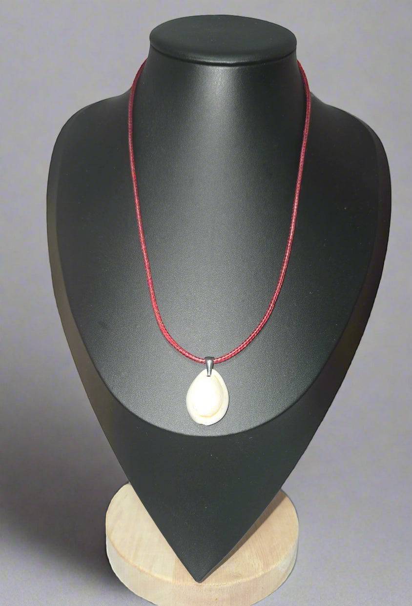 KRE PRIME handcrafted white shell pendant necklace on a red cord, displayed on a black bust.