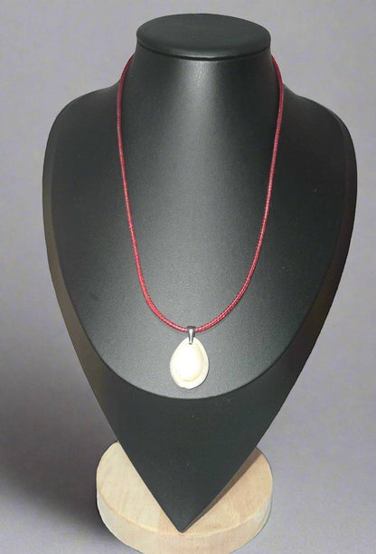 KRE PRIME handcrafted white shell pendant necklace on a red cord, displayed on a black bust.