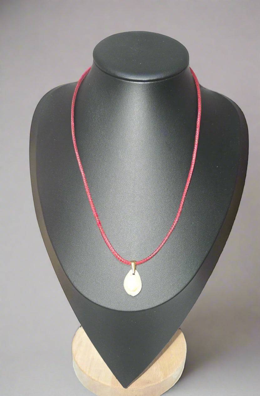 KRE PRIME handcrafted teardrop shell pendant necklace on a red cord, displayed on a black bust.